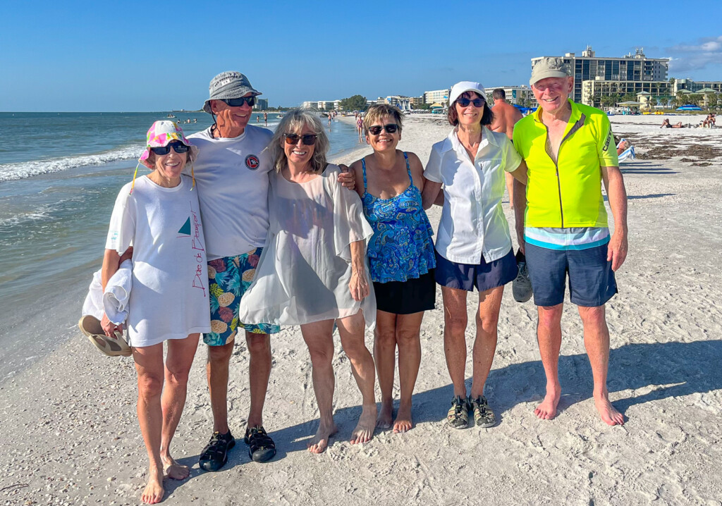 A group of people posing for a photo on a beach

Description automatically generated