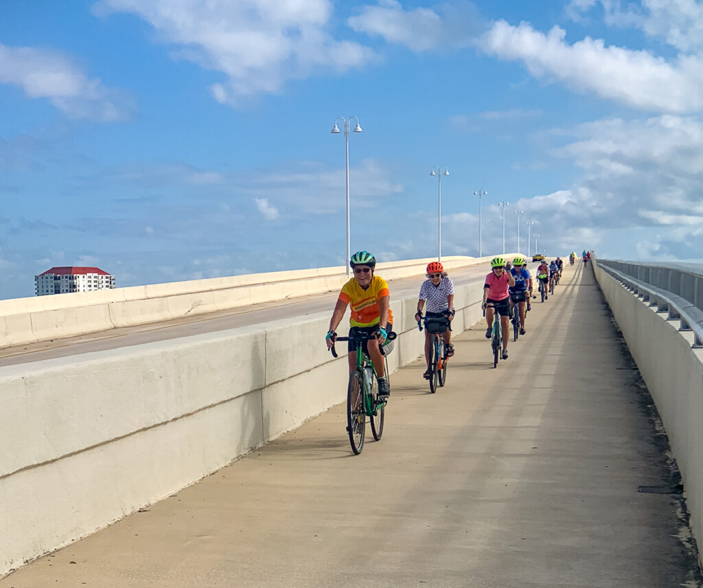 A group of people riding bikes on a bridge

Description automatically generated