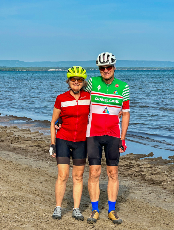 A person and person wearing cycling gear standing on a beach

Description automatically generated with low confidence