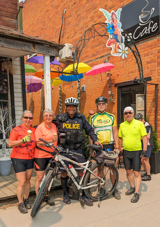 A police officer standing with a bicycle and a group of people

Description automatically generated with low confidence