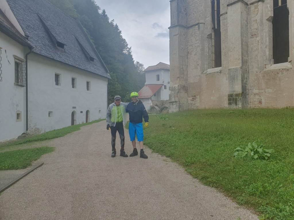 Two men standing on a path in front of a building

Description automatically generated