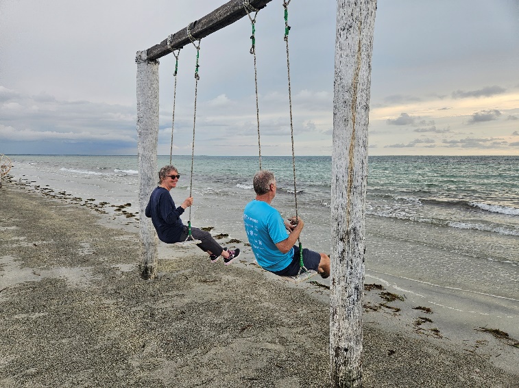 A person and person on swings on a beach

Description automatically generated