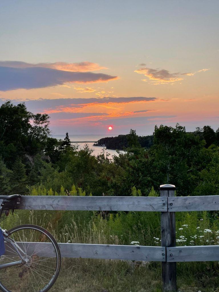 A bicycle on a fence overlooking a body of water

Description automatically generated
