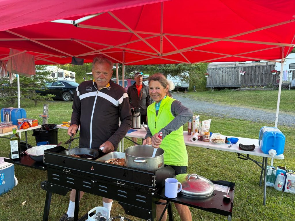 A person and person cooking food under a tent

Description automatically generated