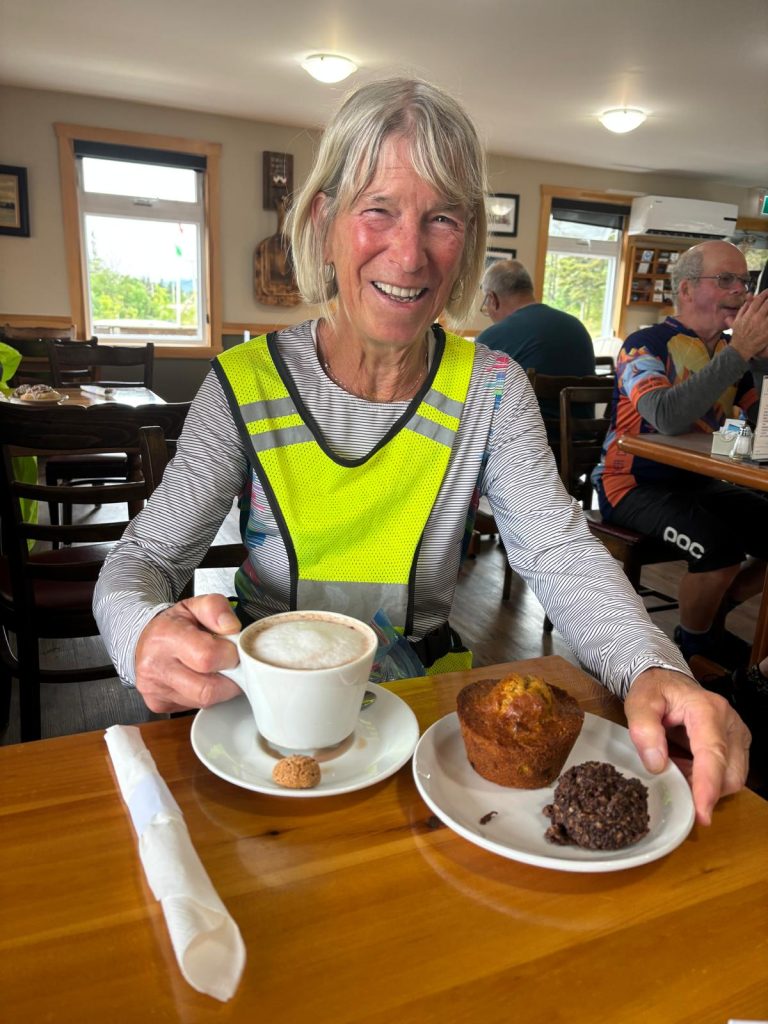 A person sitting at a table with a cup of coffee and a muffin

Description automatically generated